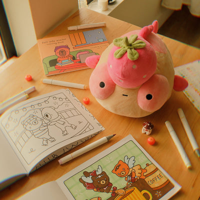 Pink plush Maxine on a table with coloring books and markers